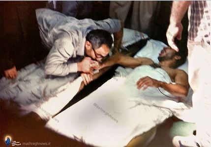 شهید سید اسدالله لاجوردی درحال بوسیدن دست یک جانباز